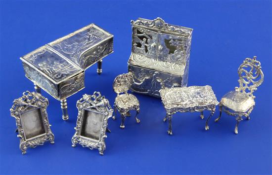 A small group of late 19th/early 20th century continental and English embossed silver miniature furniture, bookcase height 3in.